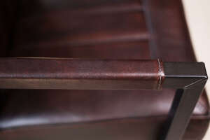 Detailaufnahme der genähten Lederarmlehne eines Schwingstuhls feine Textur des dunkelbraunen Echtleders