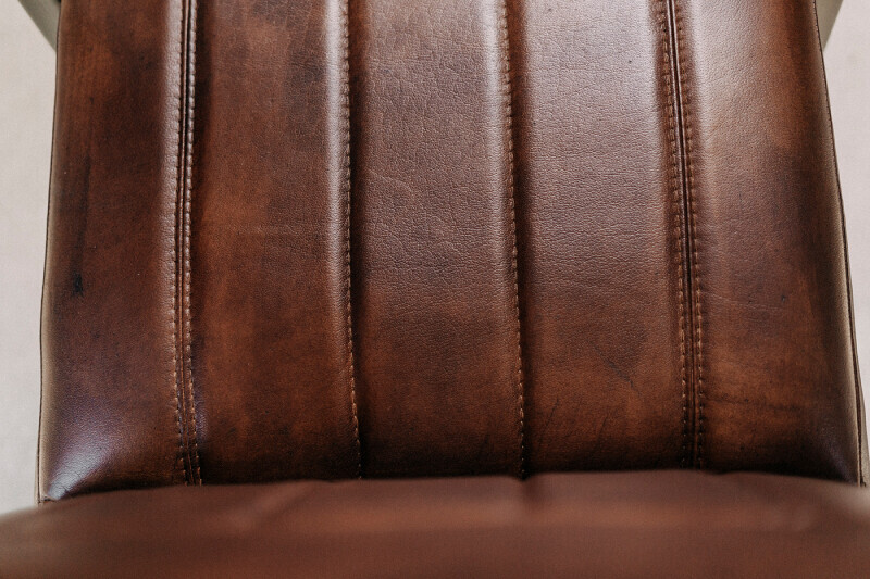 Detailaufnahme der Sitzflächenpolsterung mit braunem Leder und Ziernähten eines Freischwinger-Stuhls