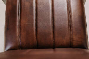 Detailaufnahme der Sitzflächenpolsterung mit braunem Leder und Ziernähten eines Freischwinger-Stuhls